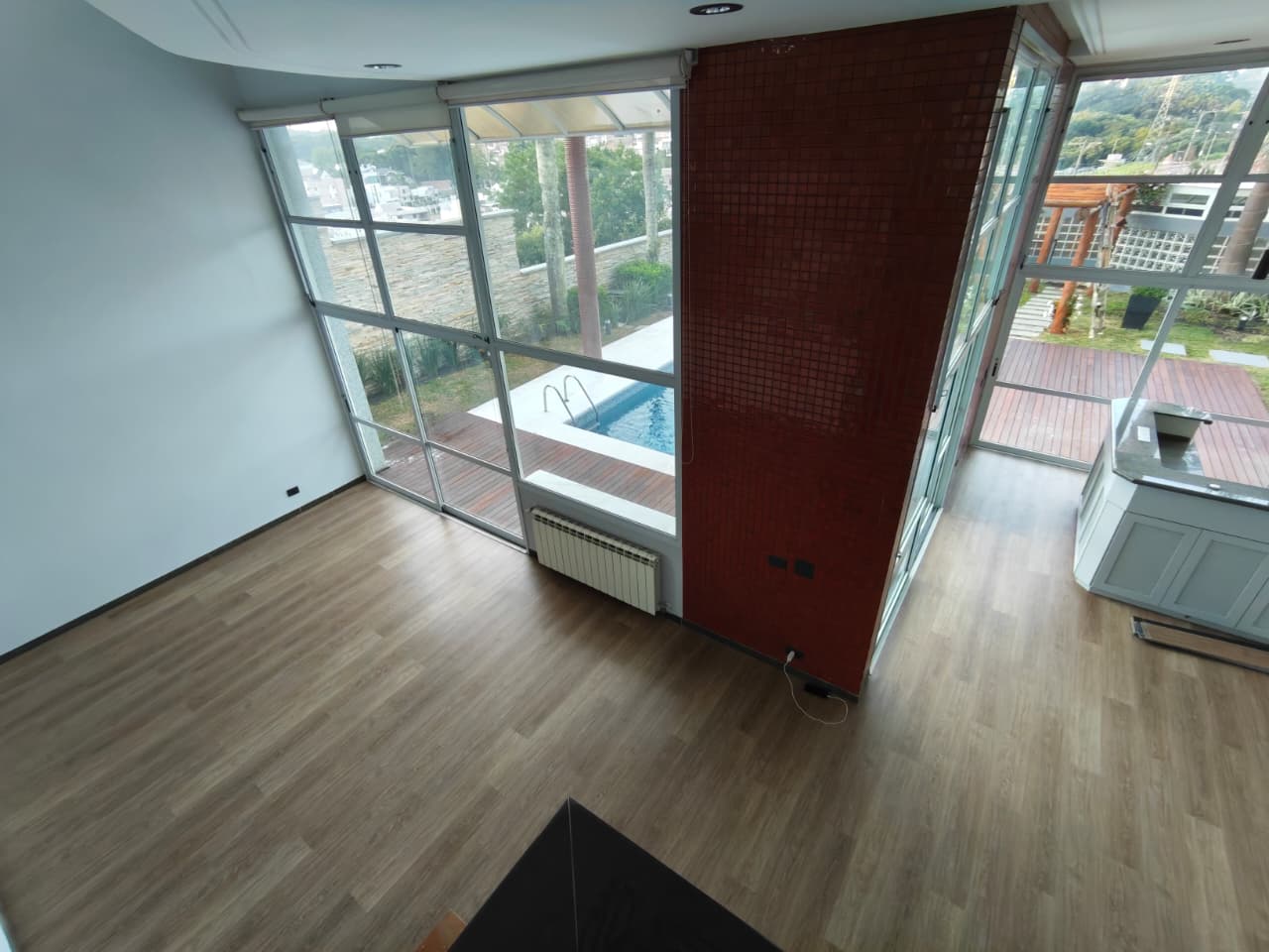 Sala com janelas panorâmicas e piso vinílico Kapazi Petrolina em madeira